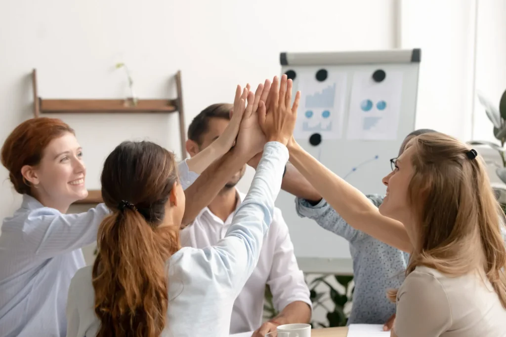 Like-minded motivated business team giving high five after successful teamwork, coaching, celebrating victory, success in career, showing unity help support. Colleagues join hands with teacher mentor